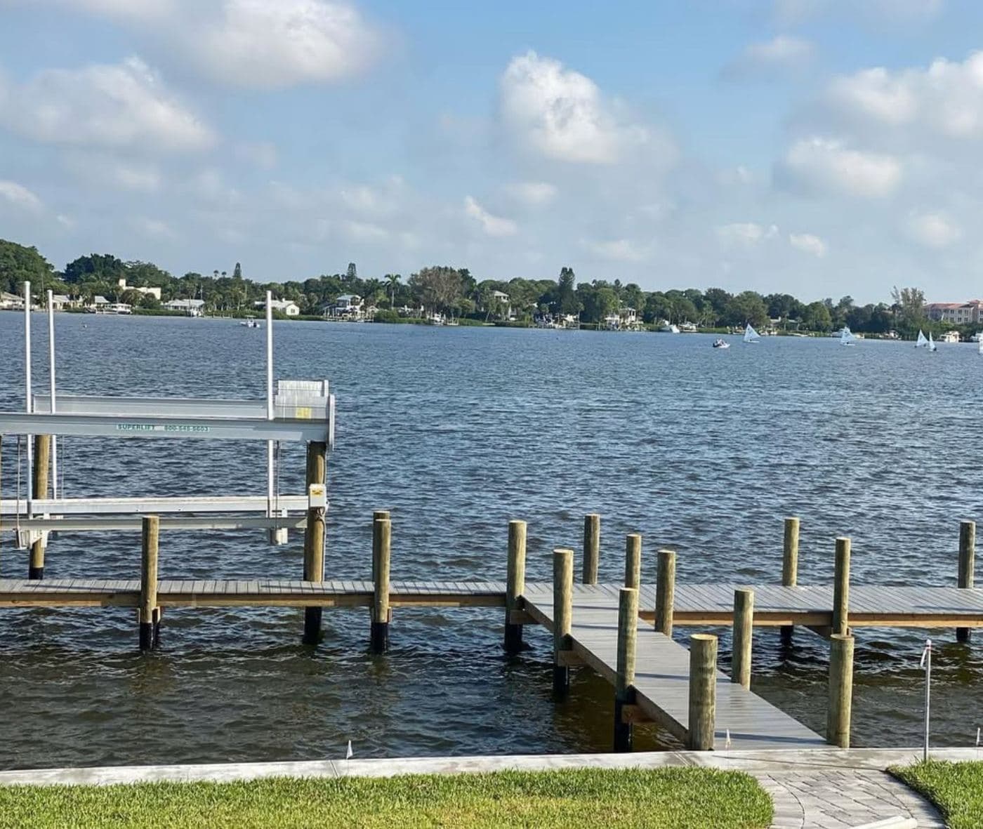 A wooden dock with a boat lift reaching into open bay water