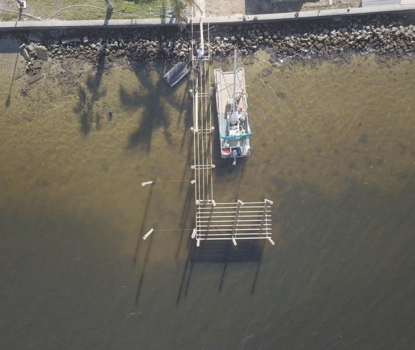 Aerial view of a dock and boat lift in shallow, clear water