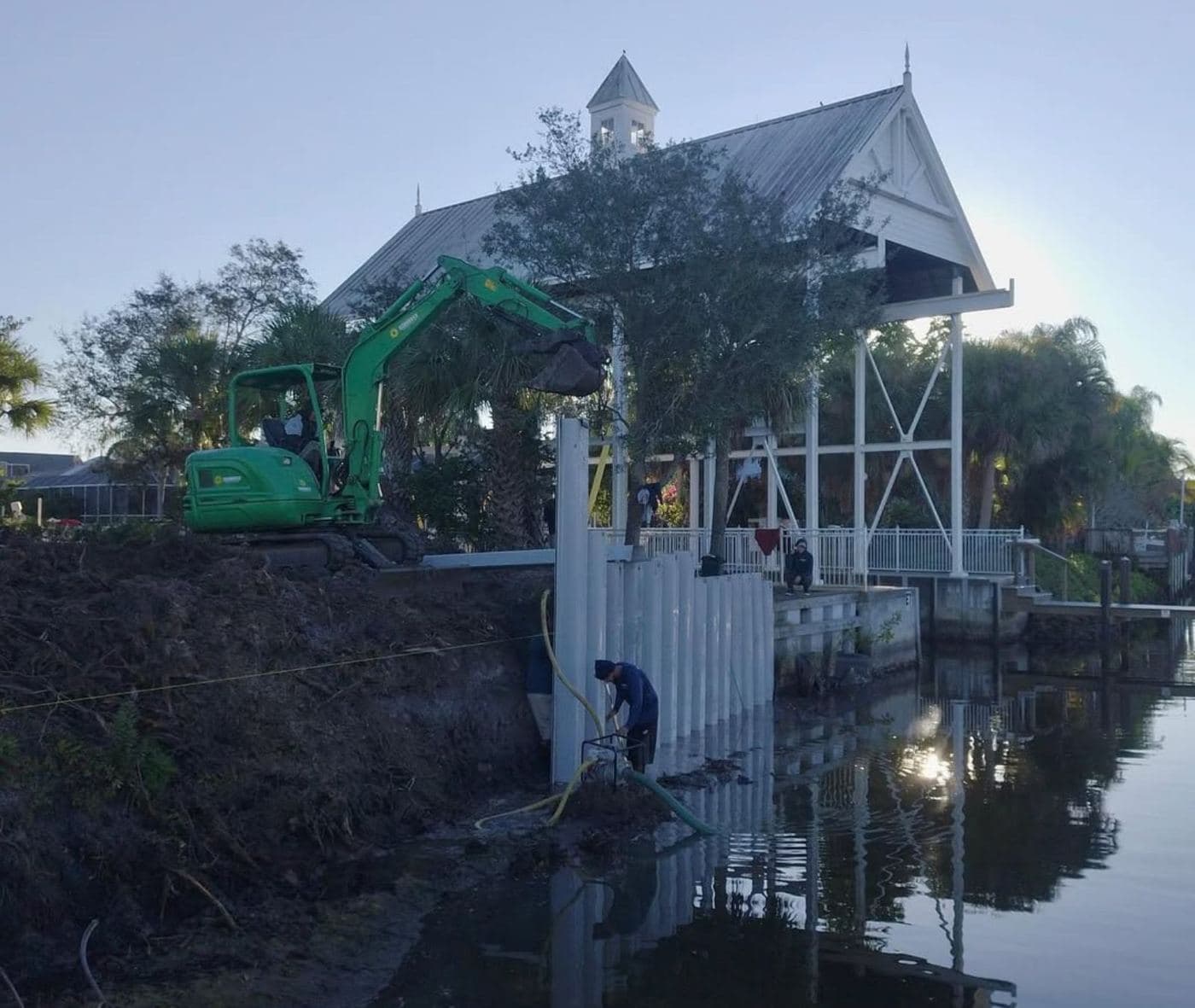Seawall construction underway with an excavator working along the shoreline