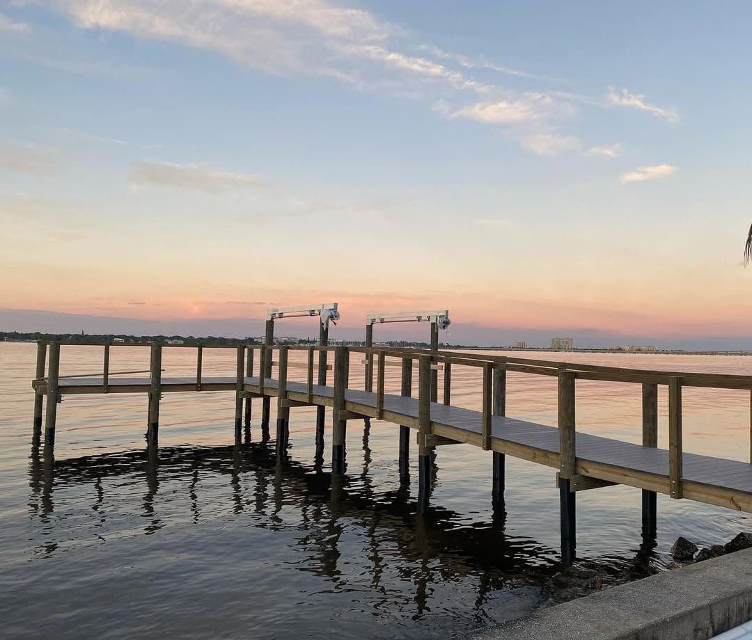 A dock and railing over still water at dusk