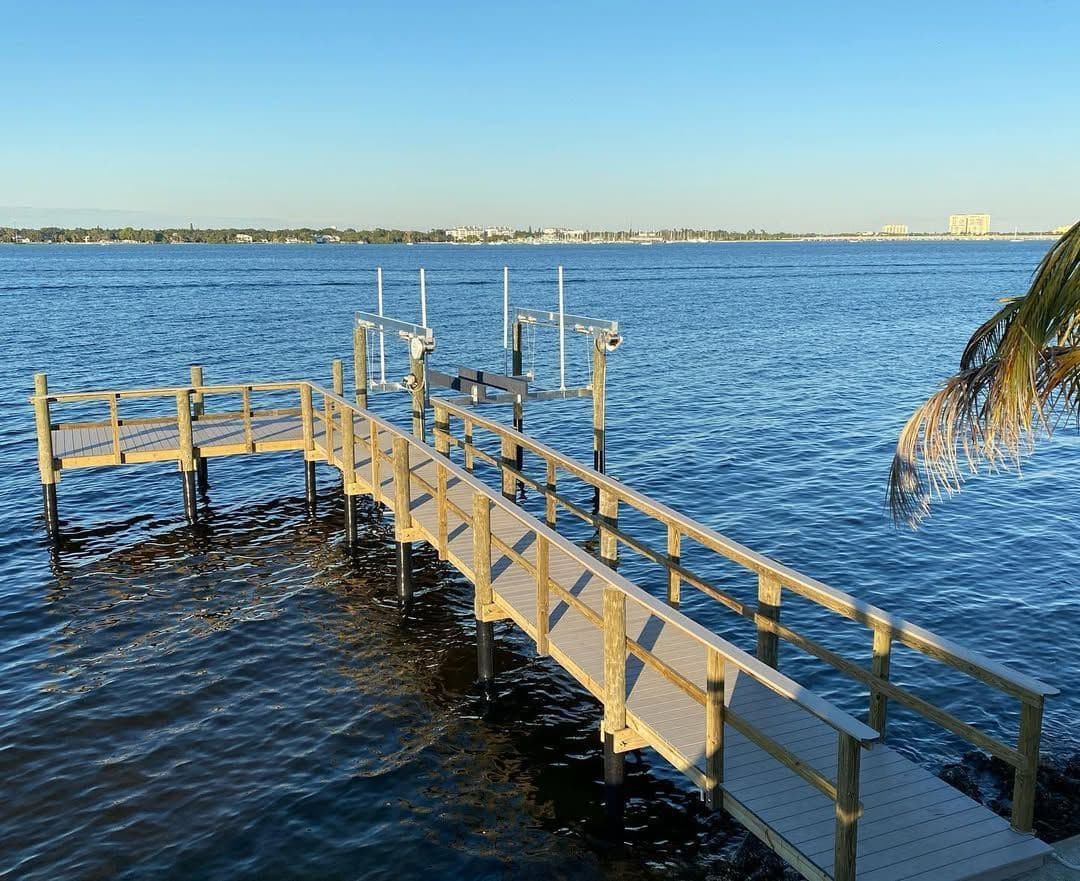 A wooden dock with railings extending over open bay water
