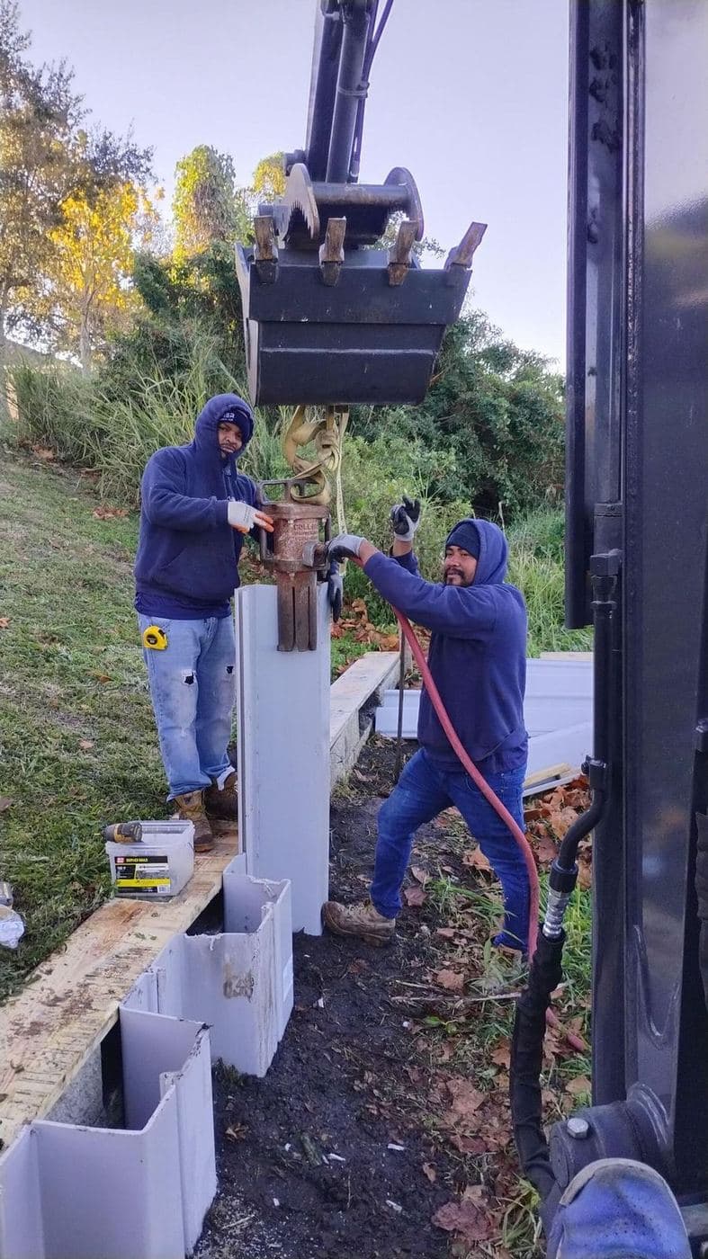 Crew members installing vinyl seawall panels from a barge