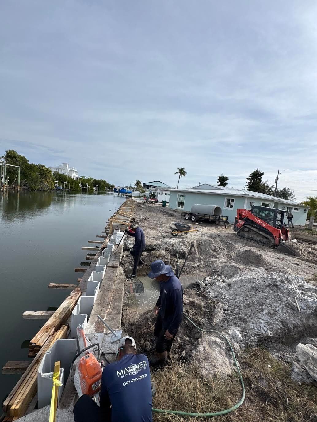 A rip-rap shoreline under construction with crew working along the bank