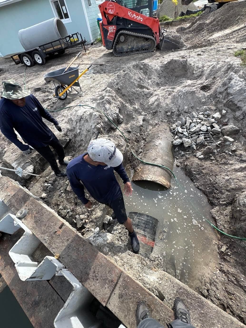 Crew installing rip-rap and seawall panels along a rocky shoreline