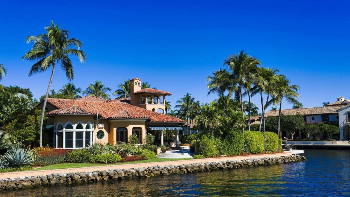 A waterfront home with a seawall and dock beneath tall palms